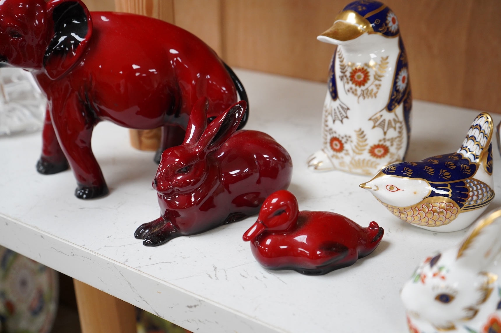 A collection of Royal Crown Derby Imari pattern paperweights, to include penguin and badger, together with three Doulton flambé animals, largest 19cm wide